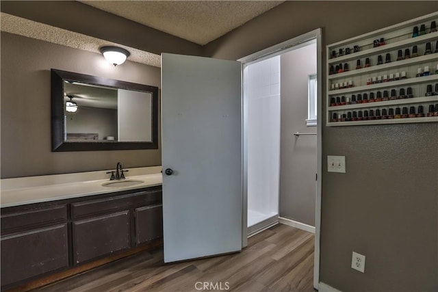 bathroom featuring vanity, baseboards, a textured ceiling, and wood finished floors