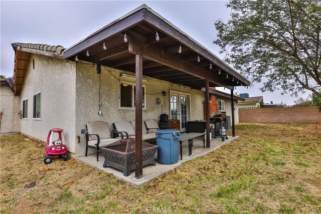 rear view of property with an outdoor fire pit, a patio area, and a lawn