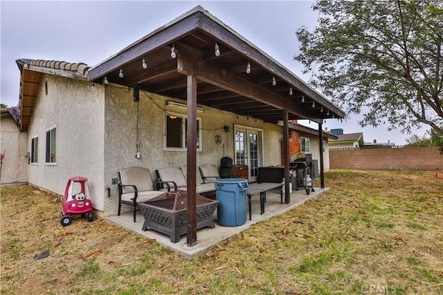 back of house with a patio, stucco siding, a lawn, an outdoor fire pit, and fence