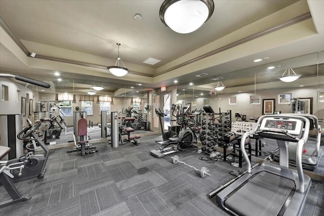 gym with a tray ceiling and dark carpet