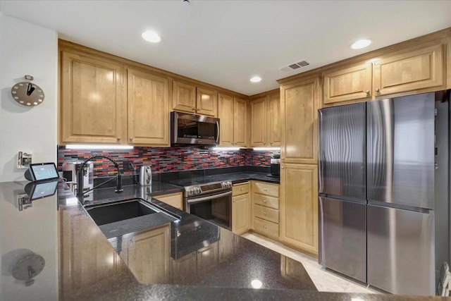 kitchen featuring stainless steel appliances, sink, dark stone countertops, and decorative backsplash