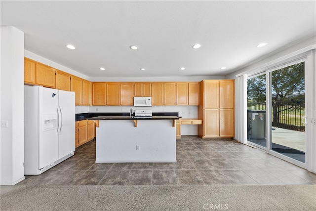 kitchen featuring a kitchen bar, white appliances, sink, and a center island with sink