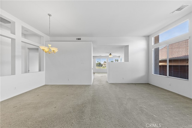 carpeted empty room featuring an inviting chandelier