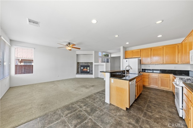 kitchen featuring white appliances, plenty of natural light, an island with sink, and dark colored carpet