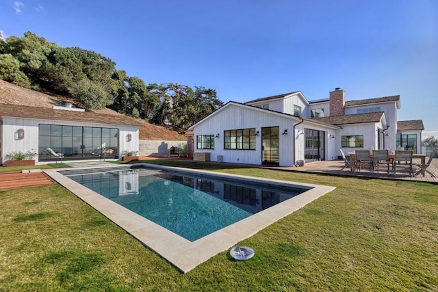 back of house with a pool side deck, a patio area, and a lawn