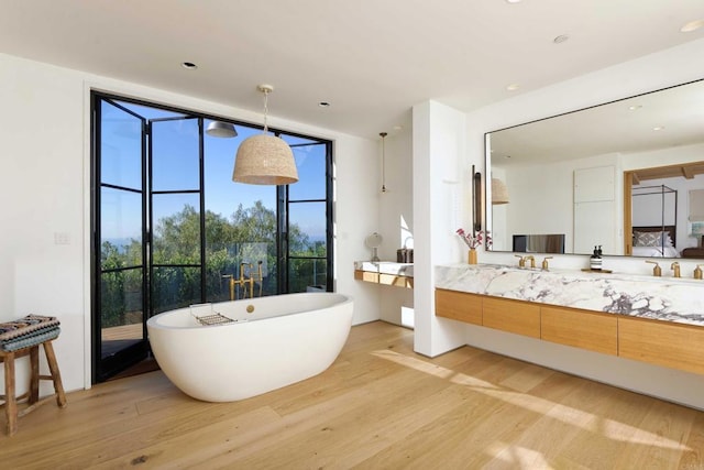 bathroom with expansive windows, vanity, hardwood / wood-style flooring, and a bath