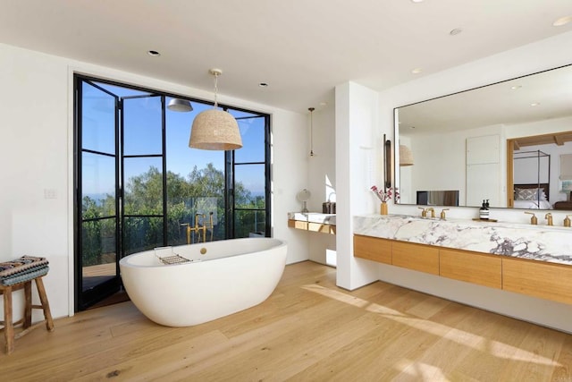 6260 Waverly Ave, La Jolla, CA 92037 - bathroom featuring wood finished floors, a freestanding bath, vanity, expansive windows, and recessed lighting