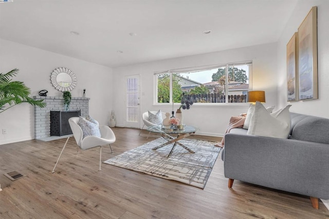 living room featuring wood-type flooring and a brick fireplace