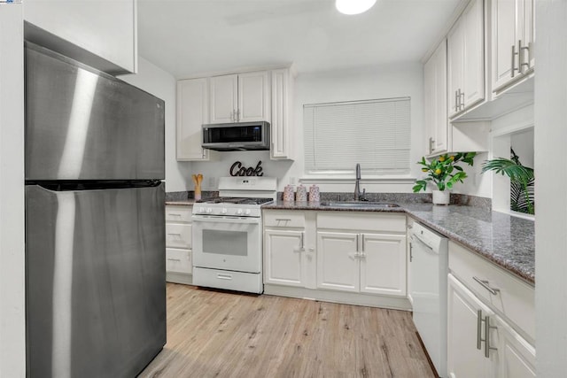 kitchen featuring sink, light hardwood / wood-style flooring, appliances with stainless steel finishes, dark stone countertops, and white cabinets