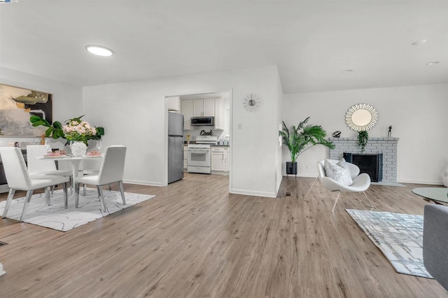 dining room with light hardwood / wood-style flooring and a fireplace