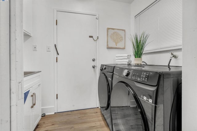 laundry room with cabinets, washing machine and clothes dryer, and light wood-type flooring