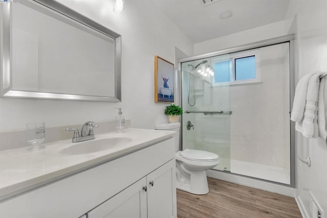 bathroom with walk in shower, vanity, toilet, and hardwood / wood-style floors