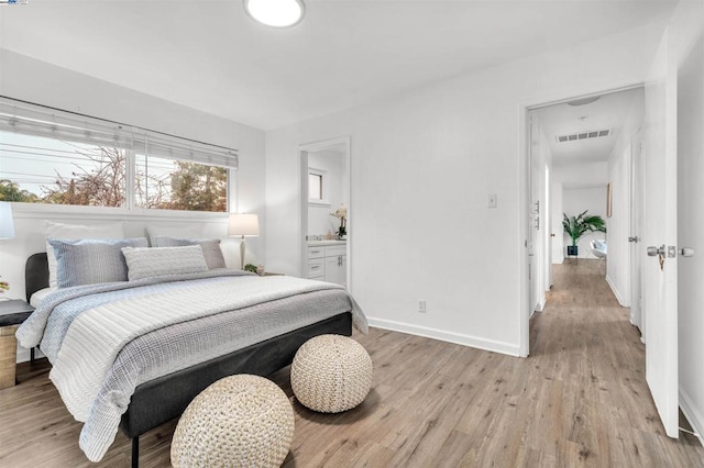 bedroom featuring ensuite bath and light wood-type flooring