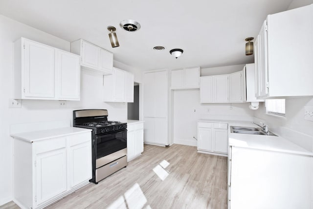 kitchen with sink, white cabinets, range with gas cooktop, and light hardwood / wood-style floors