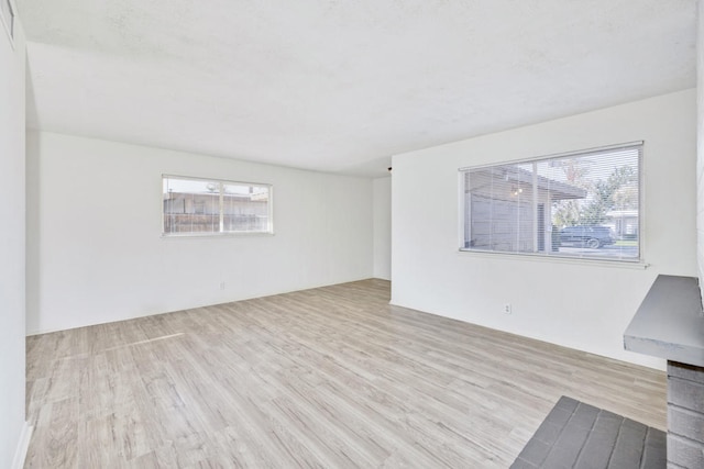 empty room with light hardwood / wood-style flooring and a healthy amount of sunlight