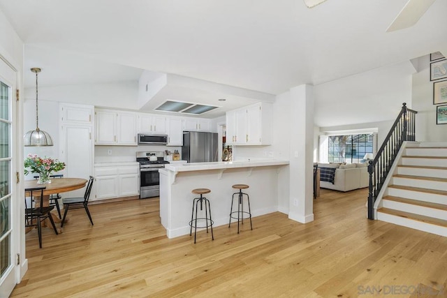 kitchen with white cabinetry, stainless steel appliances, kitchen peninsula, and light hardwood / wood-style flooring