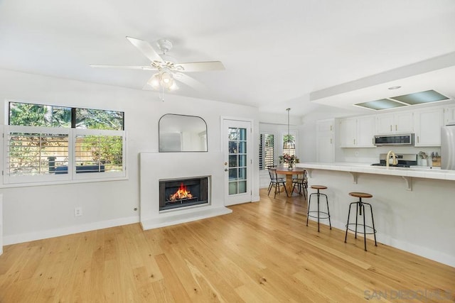 living room featuring plenty of natural light, sink, ceiling fan, and light hardwood / wood-style flooring