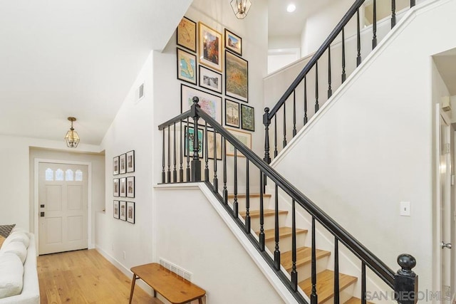 foyer featuring an inviting chandelier, light hardwood / wood-style floors, and a high ceiling