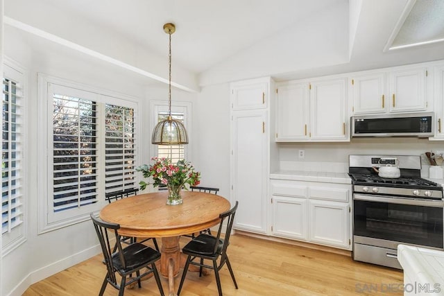 kitchen featuring stainless steel appliances, white cabinetry, light hardwood / wood-style floors, and decorative light fixtures