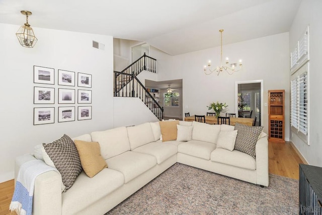 living room with a notable chandelier, wood-type flooring, and high vaulted ceiling