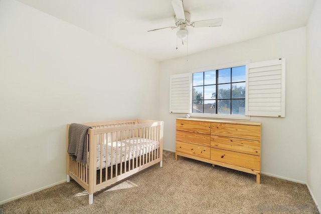 bedroom with ceiling fan, carpet floors, and a crib