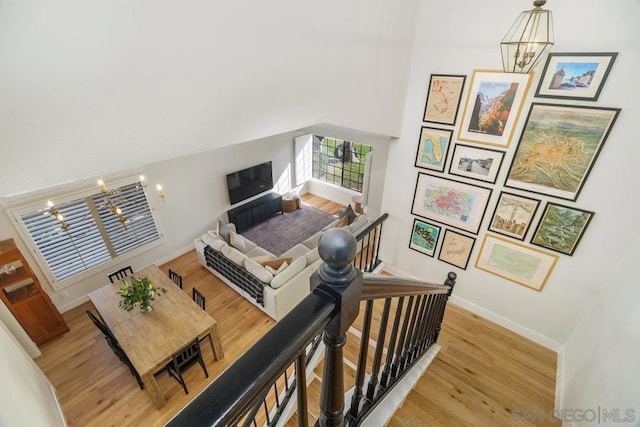 living room featuring a notable chandelier, light hardwood / wood-style floors, and a high ceiling