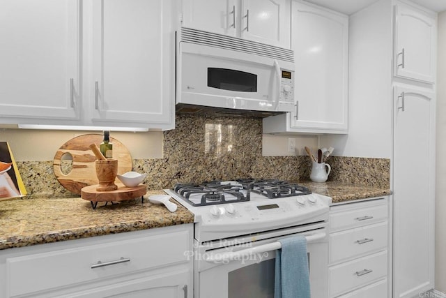 kitchen with dark stone countertops, white appliances, and white cabinets