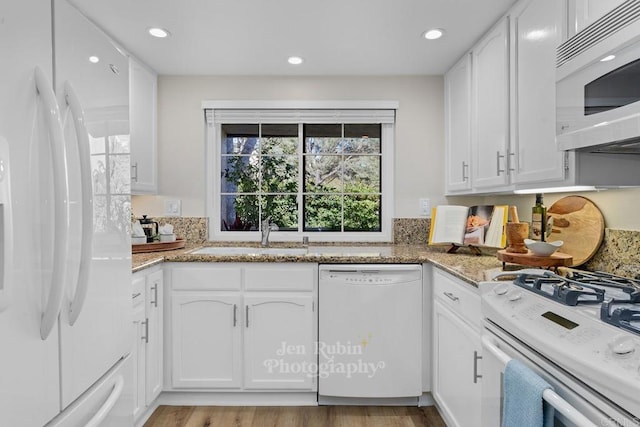 kitchen featuring sink, white cabinetry, light stone counters, white appliances, and light hardwood / wood-style floors