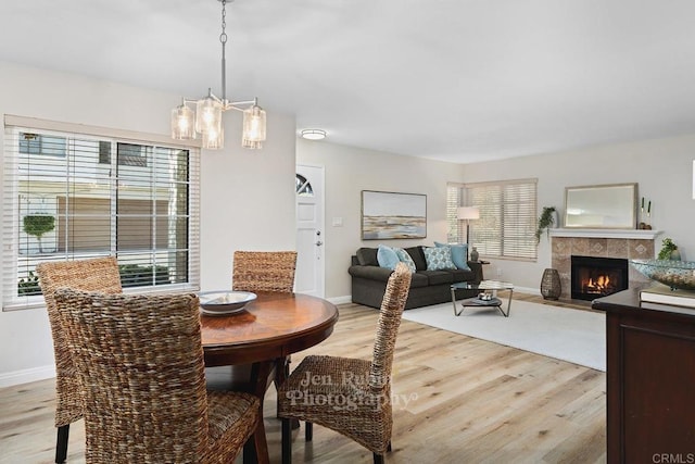 dining area with a chandelier, a fireplace, and light hardwood / wood-style flooring