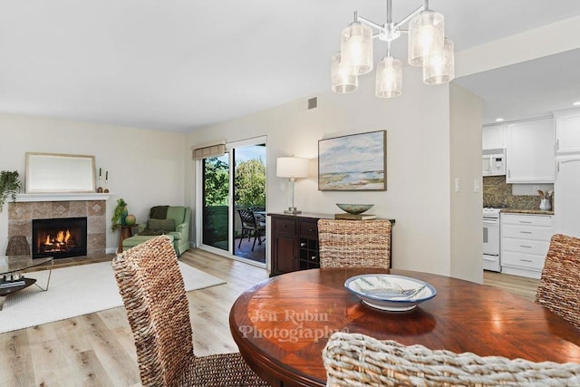 dining area with a tile fireplace and light wood-type flooring