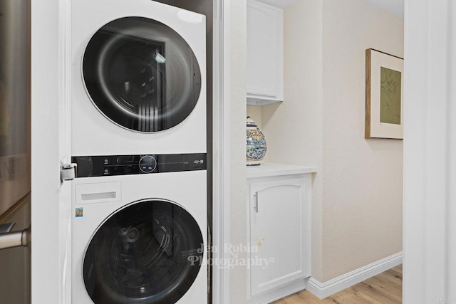 laundry area with stacked washer / dryer and light hardwood / wood-style floors