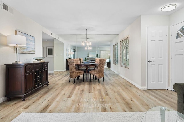 dining space featuring a wealth of natural light, a chandelier, and light hardwood / wood-style flooring