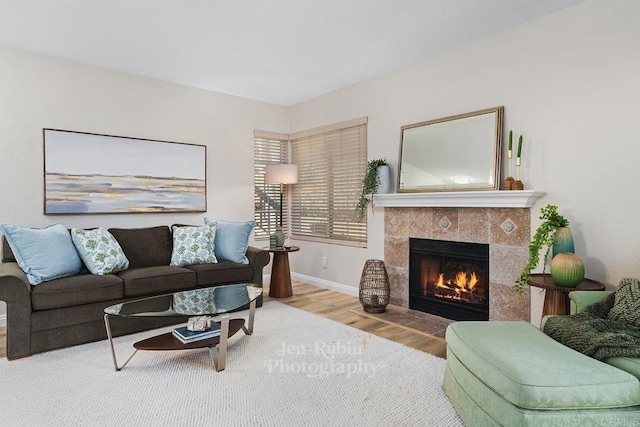 living room featuring a tiled fireplace and wood-type flooring