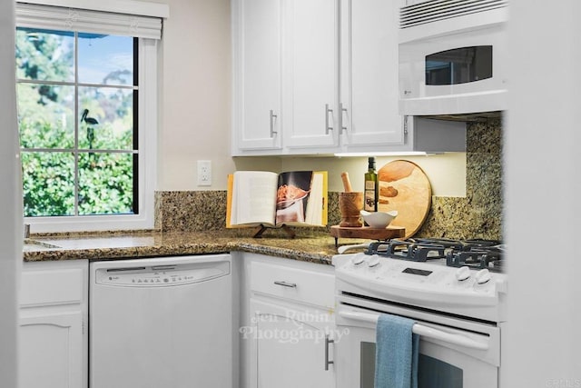 kitchen featuring white cabinetry, white appliances, and dark stone counters