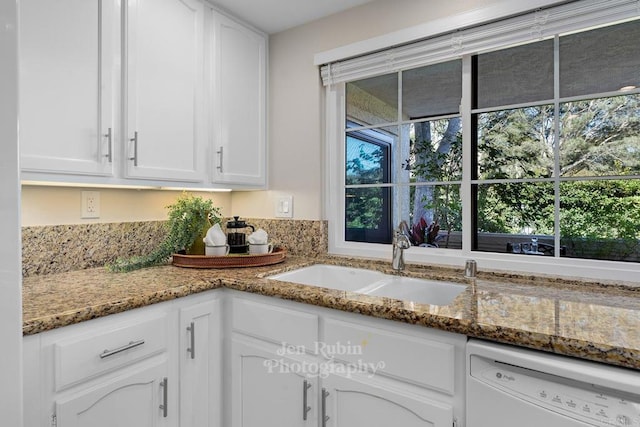 kitchen with stone counters, white dishwasher, sink, and white cabinets