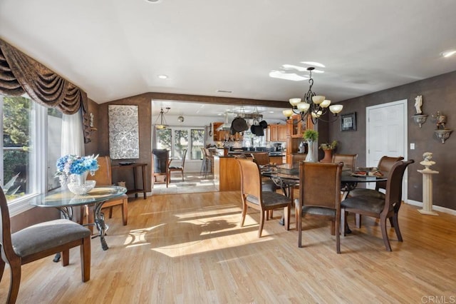 dining space featuring an inviting chandelier, lofted ceiling, and light wood-type flooring