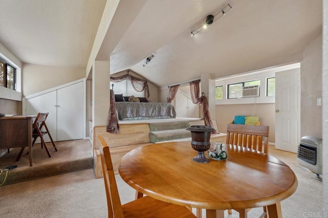 carpeted dining space featuring heating unit, a wealth of natural light, rail lighting, and vaulted ceiling