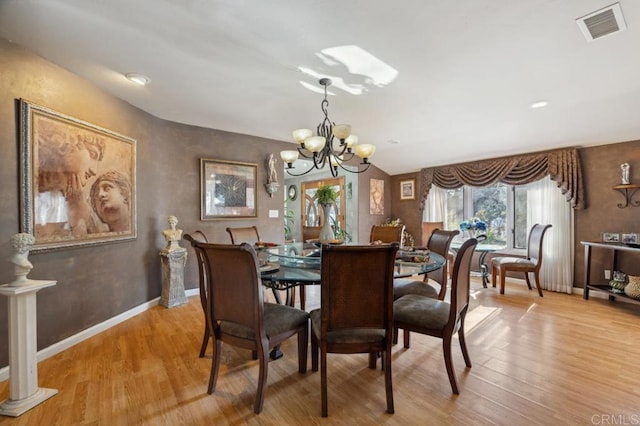 dining space with ornate columns, an inviting chandelier, and light hardwood / wood-style floors