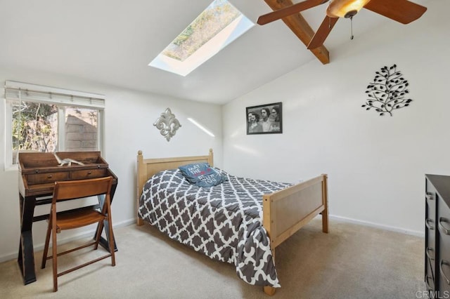 bedroom with ceiling fan, vaulted ceiling with skylight, and light carpet