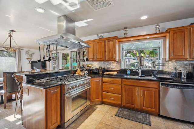 kitchen with pendant lighting, sink, stainless steel appliances, island range hood, and kitchen peninsula