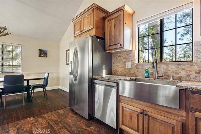 kitchen featuring light stone countertops, appliances with stainless steel finishes, sink, and lofted ceiling