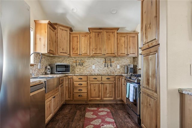 kitchen featuring tasteful backsplash, sink, dark hardwood / wood-style flooring, stainless steel appliances, and light stone countertops