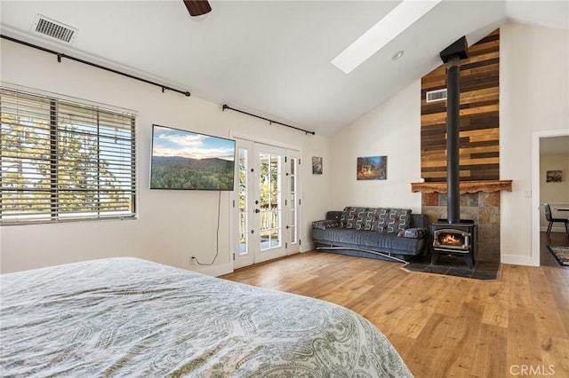 bedroom with french doors, multiple windows, a wood stove, and access to outside