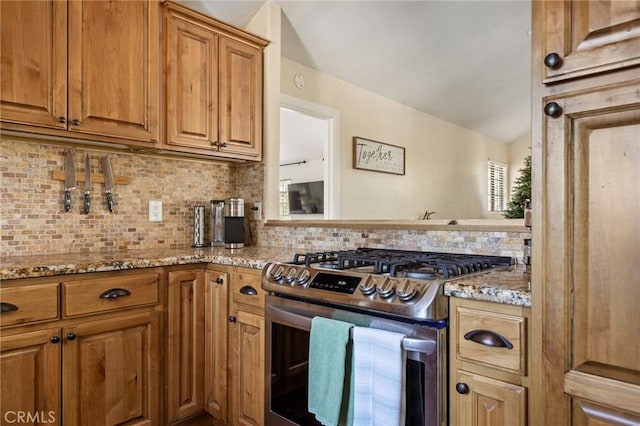 kitchen featuring light stone counters, stainless steel range with gas stovetop, and decorative backsplash