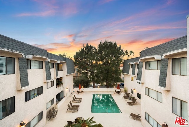 pool at dusk featuring a patio area