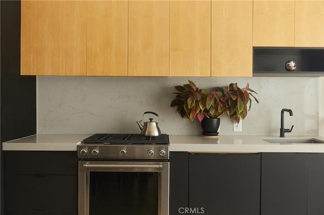 kitchen featuring sink, decorative backsplash, gas stove, and light brown cabinets