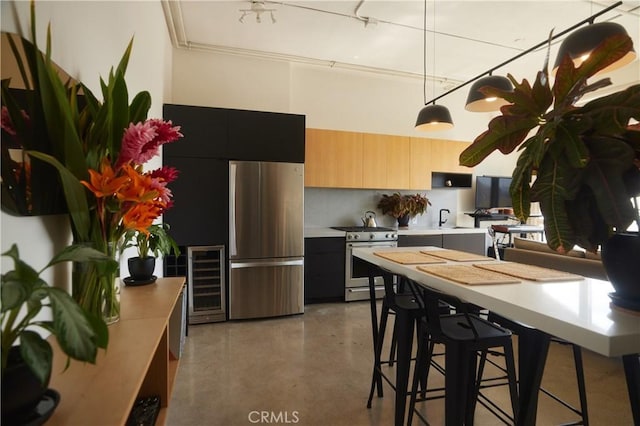 kitchen featuring sink, stainless steel appliances, a kitchen breakfast bar, wine cooler, and decorative light fixtures