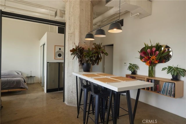 dining space featuring a towering ceiling and concrete floors