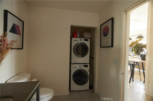 washroom with stacked washer and dryer and light tile patterned floors