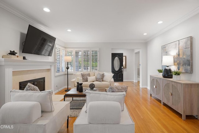 living room with ornamental molding, a premium fireplace, and light hardwood / wood-style floors